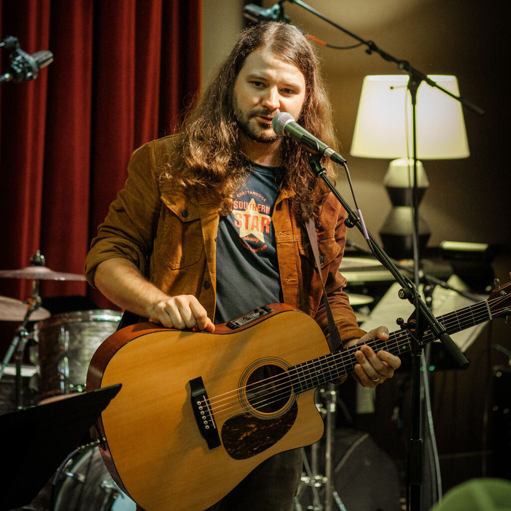 Brent Cobb holding a guitar on stage